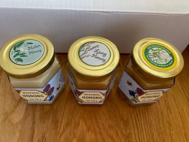 Tre burkar Bäckaskogs honung med olika etiketter